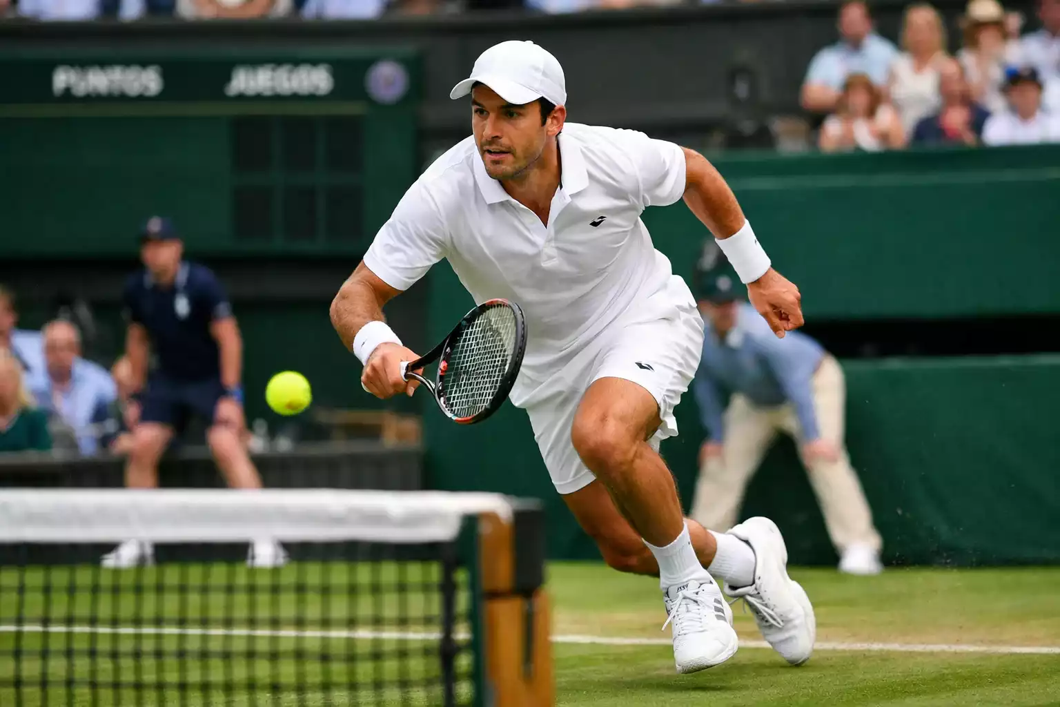 Tenista ejecutando saque y volea en césped de Wimbledon
