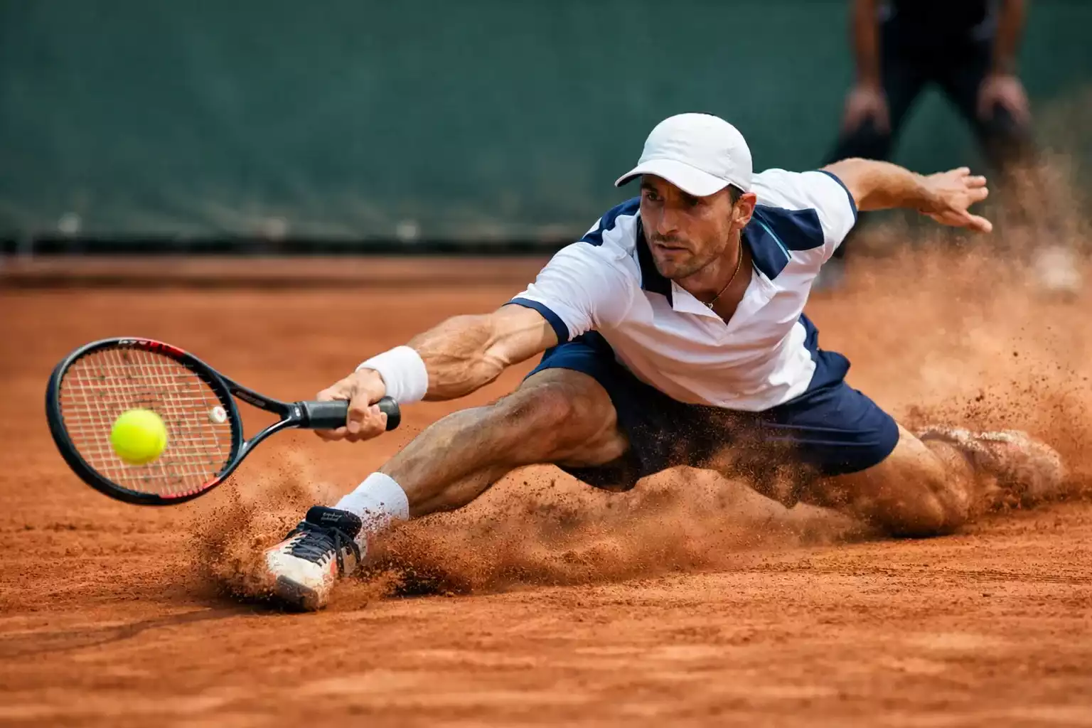 Tenista deslizándose sobre tierra batida para alcanzar la pelota